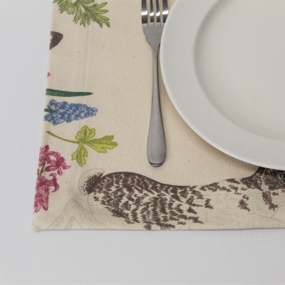 Jogo americano bege com flores e penas, prato branco e garfo