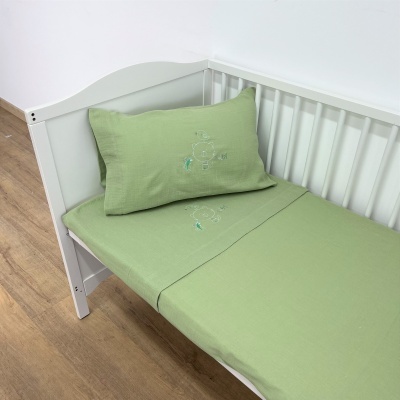 Berço branco com roupa de cama verde claro e bordado infantil