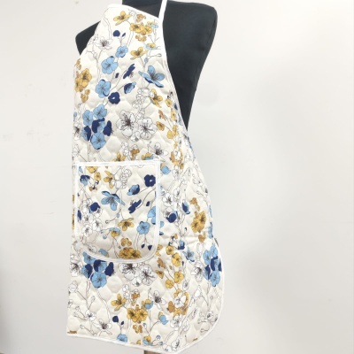 Avental branco acolchoado com flores azuis e amarelas em manequim preto