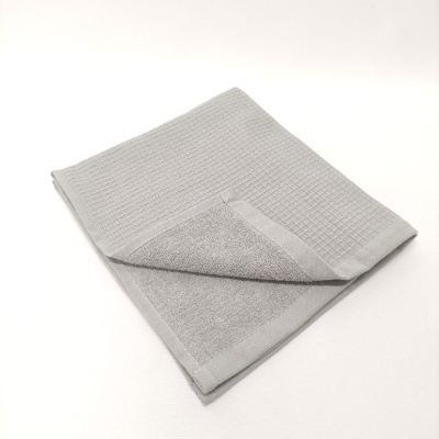 Toalha cinza de algodão com textura dupla dobrada sobre fundo branco
