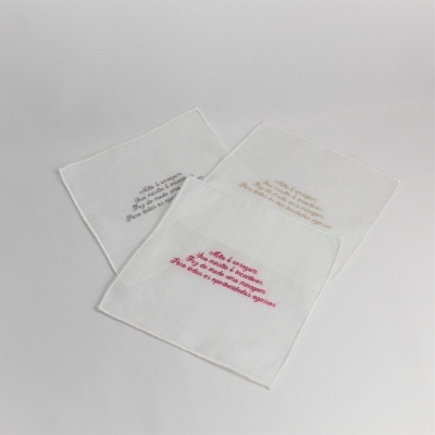 Três lenços de tecido branco com texto bordado em várias cores