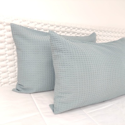 Três almofadas azuis com padrão waffle sobre superfícies brancas