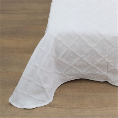 Capa de mesa branca com padrão geométrico em relevo sobre chão de madeira