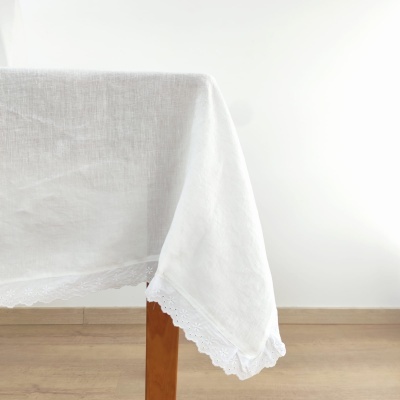 toalha de mesa branca com bordado rendilhado numa mesa de madeira clara