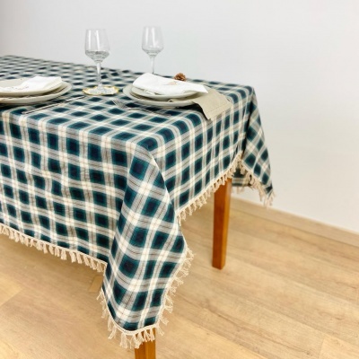 Toalha de mesa azul e bege com franjas sobre mesa de madeira