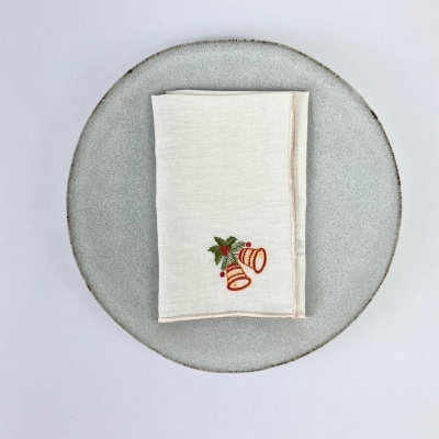 Guardanapo branco com bordado de sinos sobre prato cinza