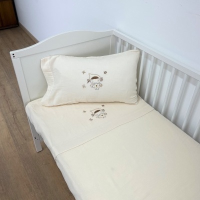 Berço branco com roupa de cama creme bordada com boneco e estrelas