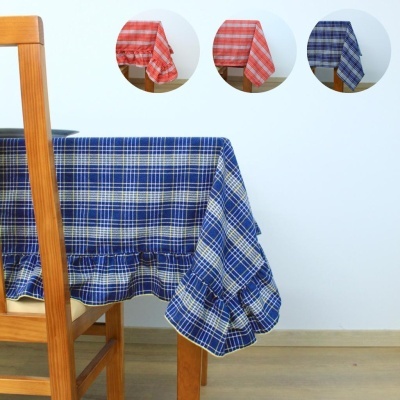 Toalha de mesa xadrez azul com babados sobre mesa e cadeira de madeira