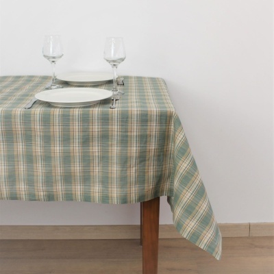 Toalha de mesa quadriculada em verde, bege e azul numa mesa de madeira com utensílios de jantar