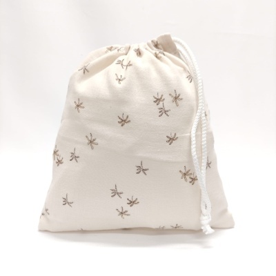 Saco de tecido branco com pequenos bordados castanhos e cordão de fecho