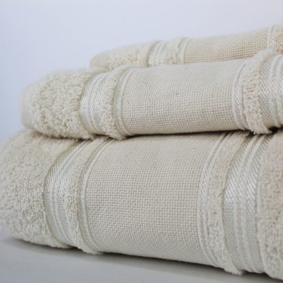Conjunto de três toalhas bege claras dobradas com faixas decorativas