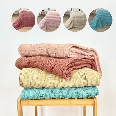 Conjunto de mantas de malha coloridas empilhadas sobre banco de madeira