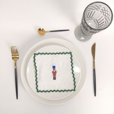 Conjunto de mesa com prato, guardanapo com figura de soldado, talheres dourados e copo de vidro