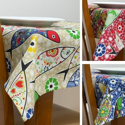 Toalhas de mesa com padrão colorido de aves e flores em mesas com cadeiras de madeira.