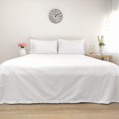 Cama de casal branca com cabeceira trançada e relógio de parede em quarto minimalista