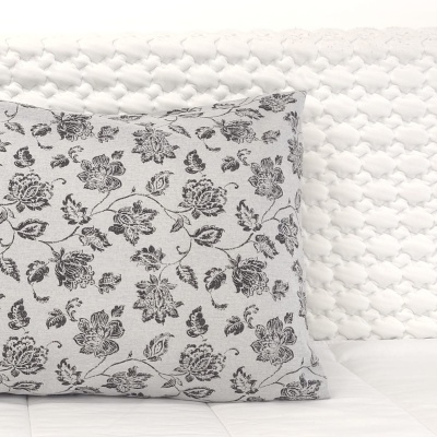 Almofada floral preta e cinza num colchão com capa branca acolchoada