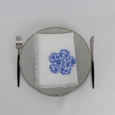 Talheres com garfo e faca, prato cinza e guardanapo branco com padrão azul