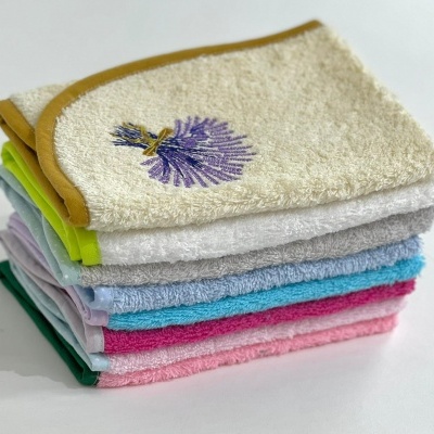 pilha de toalhas de várias cores com bordado roxo na toalha superior