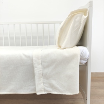 Berço branco com roupa de cama creme em ambiente minimalista