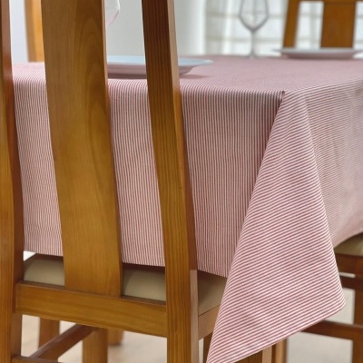 Toalha de mesa com riscas vermelhas e brancas sobre mesa de madeira com cadeiras de madeira