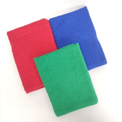 Três panos de microfibra nas cores vermelho, azul e verde dobrados sobre superfície branca