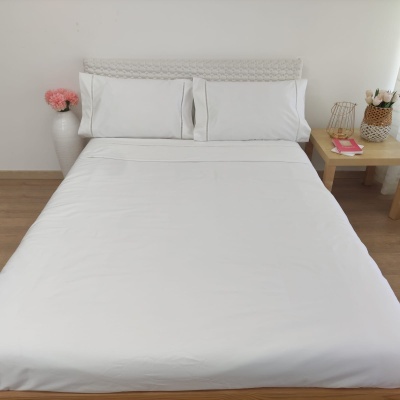 Cama com roupa de cama branca e decoração minimalista acolhedora