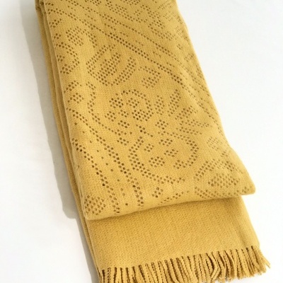 Manta amarelo com padrão de buracos e franjas