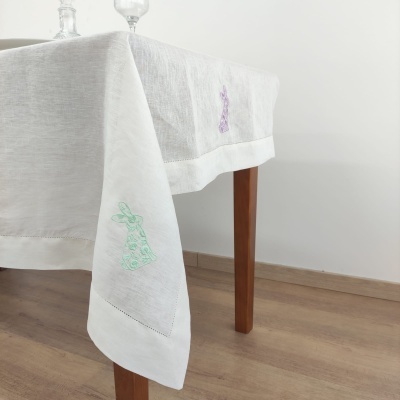 Toalha de mesa branca com bordados coloridos em mesa de madeira