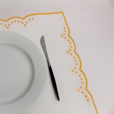 Toalha de mesa branca bordada em amarelo com prato e faca
