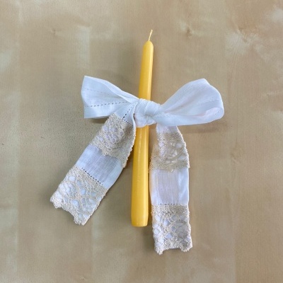 Vela amarela com laço branco decorativo e renda bege