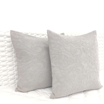 Duas almofadas cinza claro com padrão floral em relevo sobre superfície branca acolchoada
