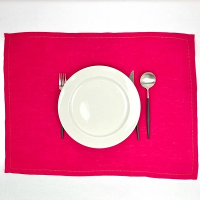 Conjunto de refeição com prato branco e talheres sobre individual rosa em tecido