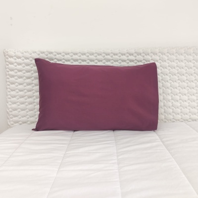 Travesseiro vinho em colchão branco acolchoado com cabeceira texturizada branca