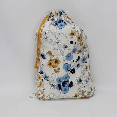 Saco de tecido branco com flores azuis, amarelas e pretas e cordão amarelo