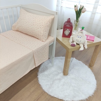 Cama de criança com lençóis florais e mesa ao lado com decoración