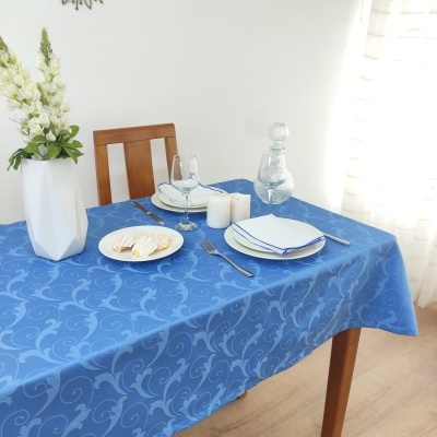 Toalha de mesa azul com padrão floral e pratos brancos numa mesa de madeira