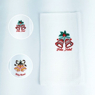 Toalha branca com bordado de sinos vermelhos e folhagem verde com texto 'Feliz Natal'