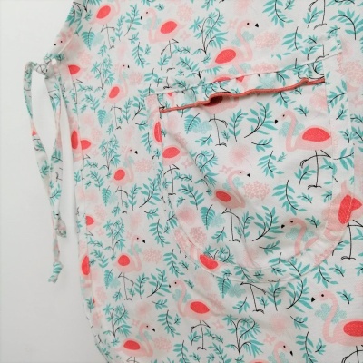 Pano branco com padrão de flamingos, flores e plantas e um cordão lateral