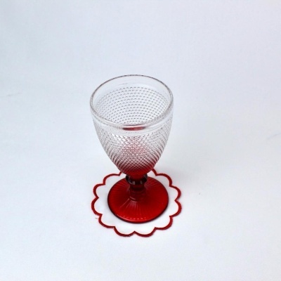 Cálice de vidro transparente com base vermelha sobre suporte de feltro vermelho