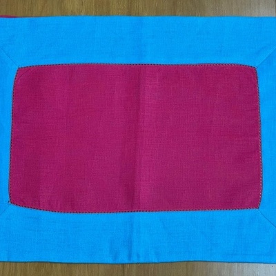 Tapete retangular vermelho com borda azul sobre piso de madeira