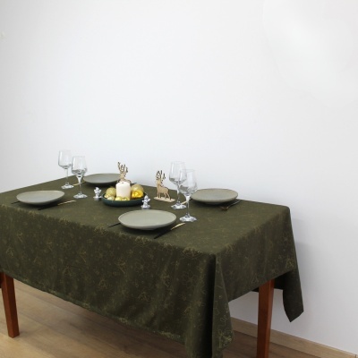 Mesa de jantar com toalha verde, pratos cinzentos, copos de vinho, velas e decoração de coelhos e árvores em madeira