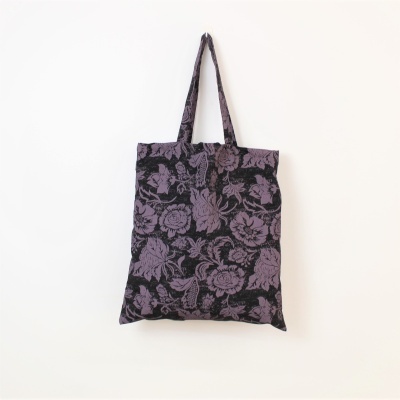 Saco de tecido com padrão floral roxo e preto pendurado na parede