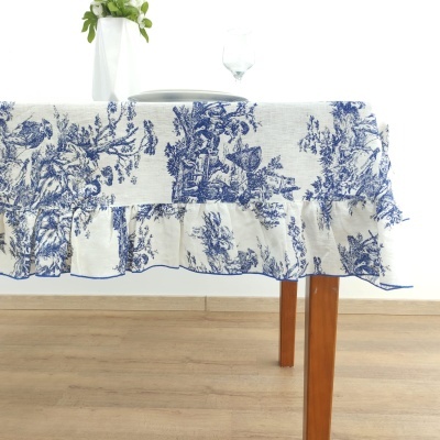 Toalha de mesa azul e branca com babado em mesa de madeira