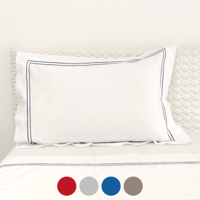 almofada branca retangular com linhas azuis sobre cama branca texturizada