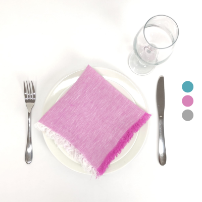 Conjunto de talheres, prato branco com guardanapo rosa/lilás e copo de vidro sobre superfície branca