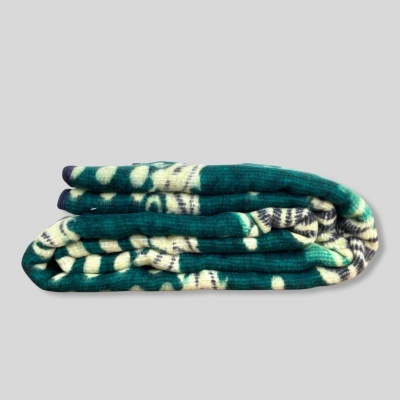 Manta dobrada com padrão azul-petróleo, branco e cinzento