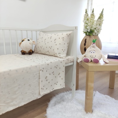 Cama infantil com roupa de cama bege com padrão floral e peluches ao lado