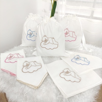 Sacos de tecido branco e panos de boca com bordados de ursinhos em azul, bege e rosa