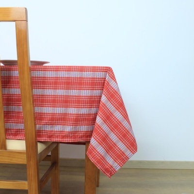Toalha de mesa xadrez vermelho e branco sobre mesa de madeira com cadeira perto