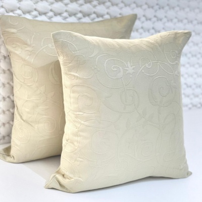 Duas almofadas quadradas bege claro com padrão texturizado arabescos